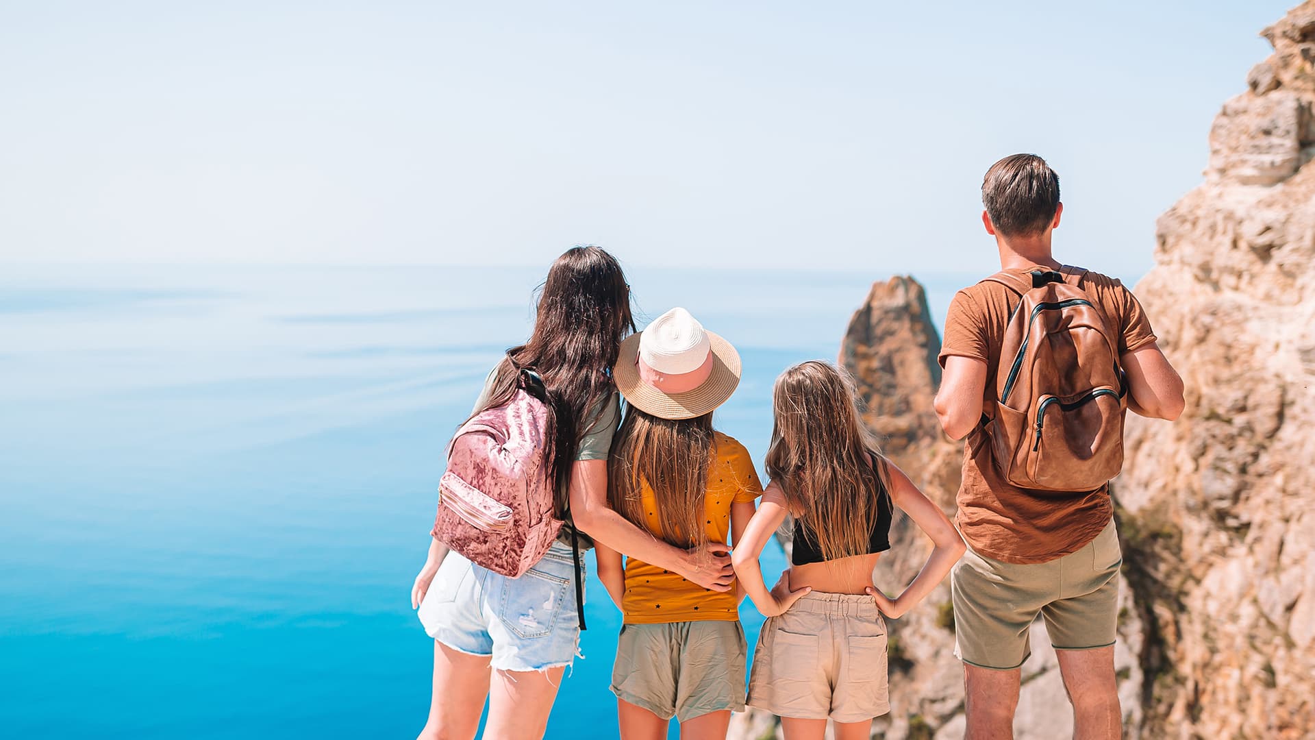 Una familia de cuatro personas contemplando el mar desde un acantilado durante un viaje